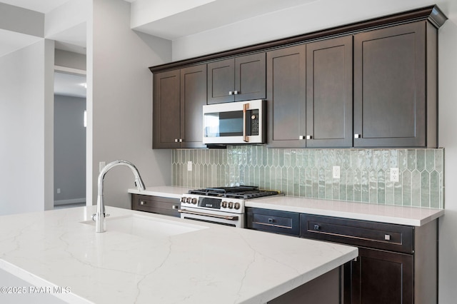 kitchen with high end stove, dark brown cabinets, light stone counters, a sink, and decorative backsplash