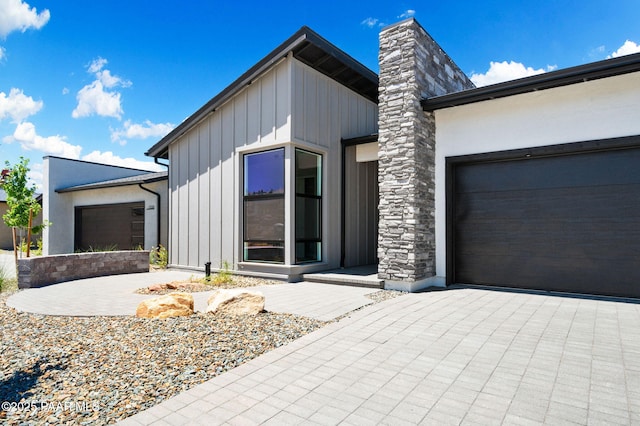 view of front of property featuring an attached garage, board and batten siding, a chimney, and driveway