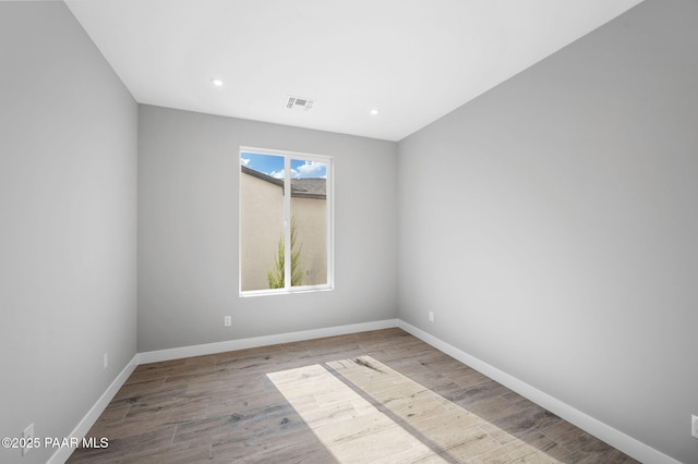 spare room featuring visible vents, baseboards, recessed lighting, and wood finished floors