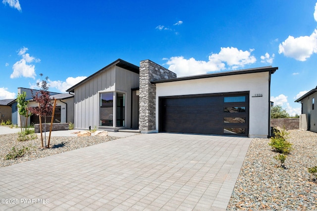 modern home with board and batten siding, a garage, and driveway