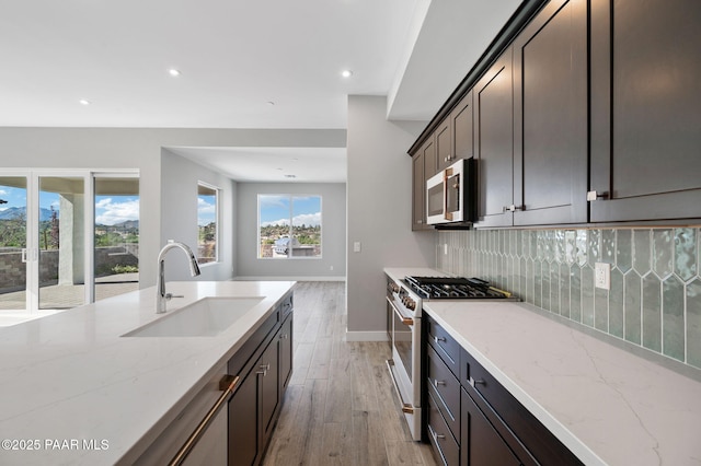 kitchen featuring white gas stove, stainless steel microwave, a sink, light wood finished floors, and backsplash