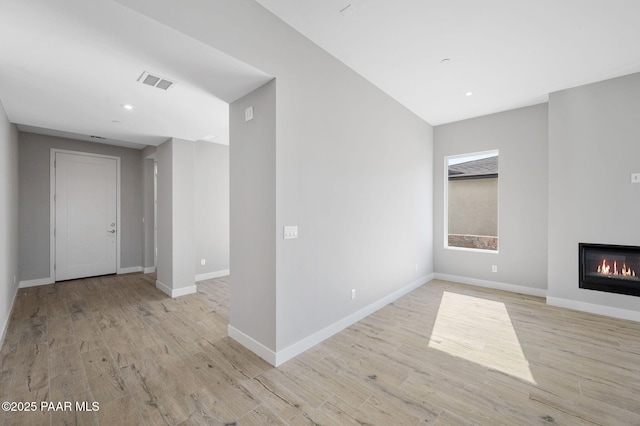 unfurnished living room featuring light wood-style flooring, baseboards, and visible vents