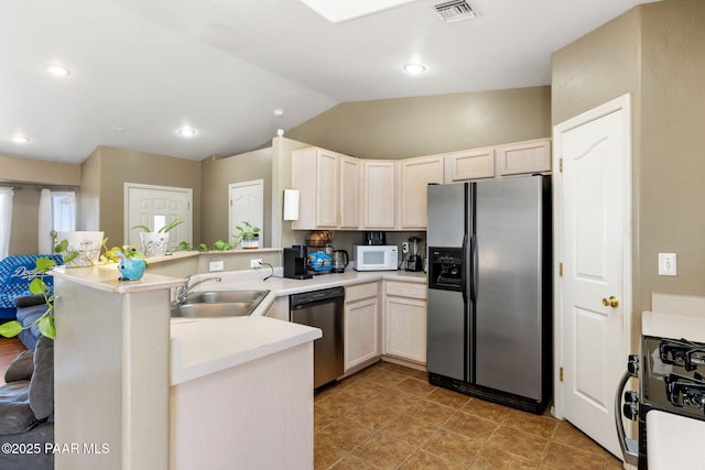 kitchen featuring visible vents, light brown cabinets, a sink, appliances with stainless steel finishes, and a peninsula