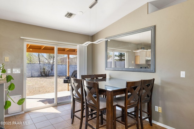 dining space featuring visible vents, baseboards, tile patterned flooring, and vaulted ceiling