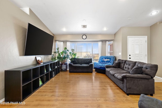 living area with light wood finished floors, baseboards, lofted ceiling, and visible vents