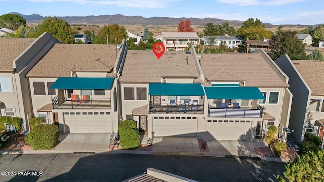 view of property featuring a mountain view, a balcony, and a garage