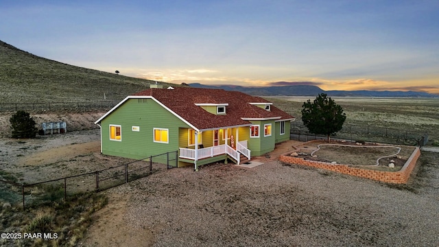 16025 N Hereford Rd, Chino Valley, AZ 86323 - back of house at dusk with covered porch, a mountain view, a fenced backyard, and roof with shingles