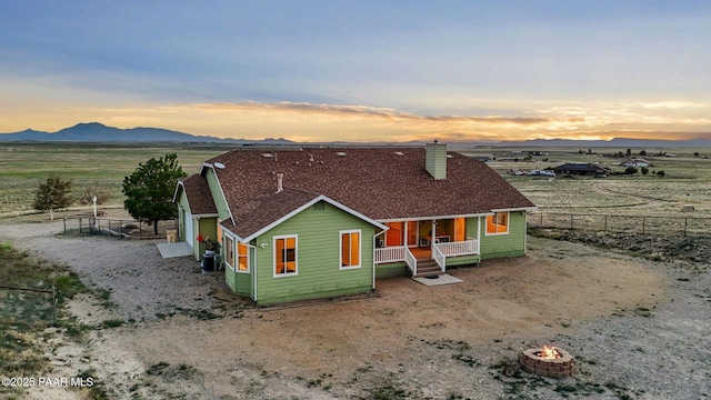 16025 N Hereford Rd, Chino Valley, AZ 86323 - back of property at dusk with central AC unit, covered porch, a chimney, an outdoor fire pit, and a mountain view