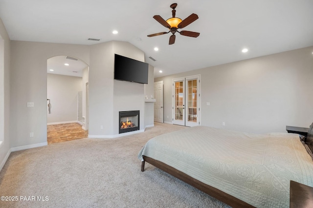 16025 N Hereford Rd, Chino Valley, AZ 86323 - bedroom featuring arched walkways, recessed lighting, light carpet, lofted ceiling, and a glass covered fireplace