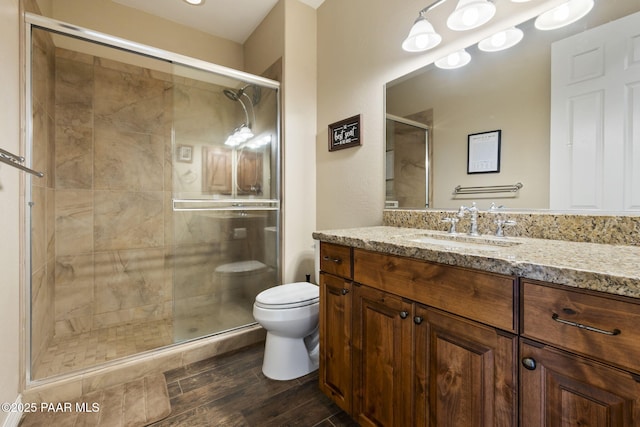 bathroom with vanity, a stall shower, toilet, and wood finished floors