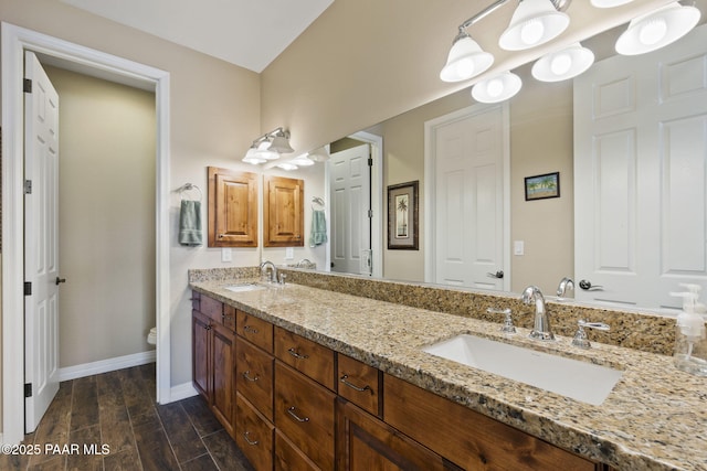 full bathroom with double vanity, a sink, wood finished floors, and toilet