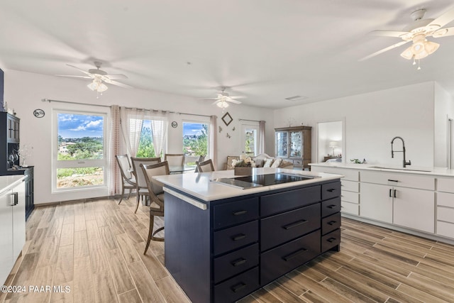 kitchen with a center island, sink, light hardwood / wood-style floors, black electric cooktop, and white cabinets