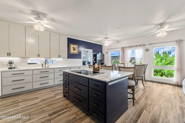 kitchen with white cabinetry, a center island, stainless steel stovetop, and light hardwood / wood-style flooring