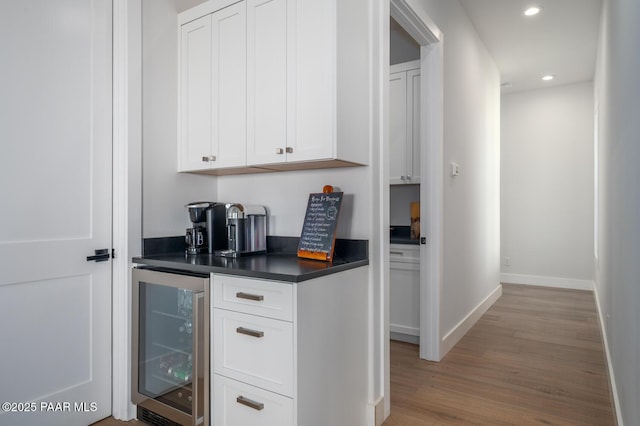 bar featuring wine cooler, recessed lighting, a bar, wood finished floors, and baseboards