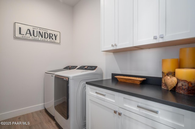 clothes washing area with cabinet space, baseboards, light wood-style floors, and independent washer and dryer