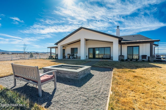 back of house featuring a fire pit, a patio, fence, a yard, and board and batten siding