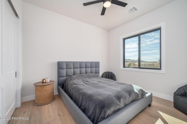 bedroom with a closet, visible vents, ceiling fan, wood finished floors, and baseboards