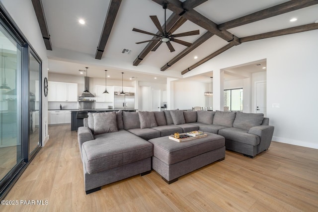 living room with vaulted ceiling with beams, a ceiling fan, baseboards, visible vents, and light wood-style floors