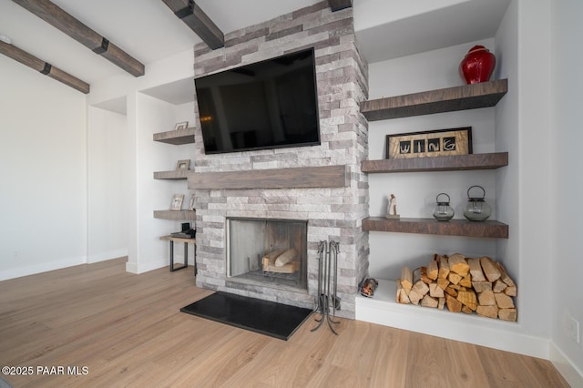 living room with a large fireplace, wood finished floors, beam ceiling, and baseboards