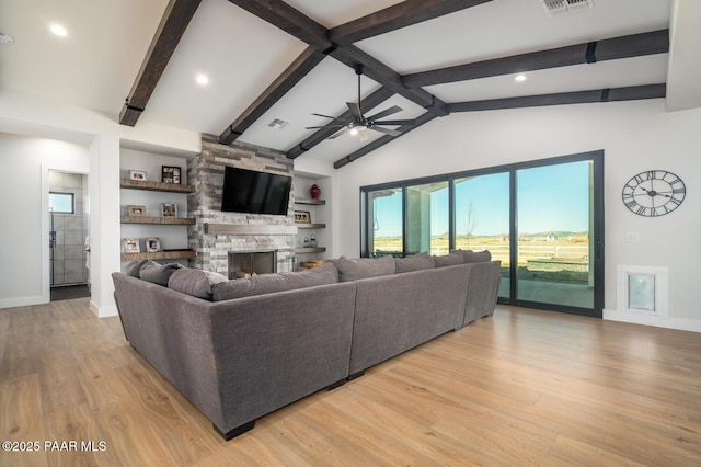 living room with a fireplace, visible vents, lofted ceiling with beams, light wood-style floors, and ceiling fan