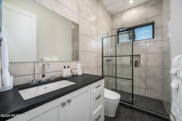 bathroom with toilet, vanity, tile walls, a shower stall, and tasteful backsplash