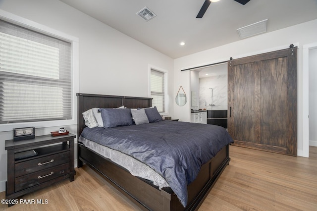 bedroom with light wood-style floors, visible vents, and multiple windows