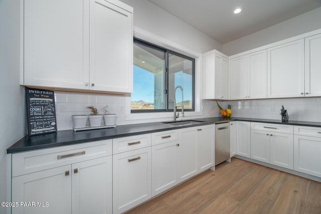 kitchen featuring light wood-style floors, dark countertops, white cabinets, and a sink