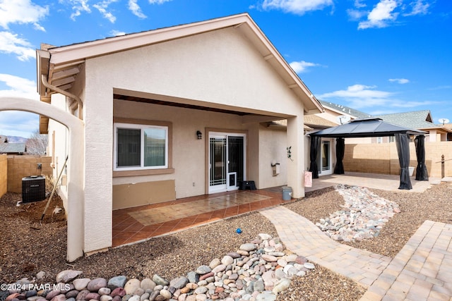 back of house featuring a gazebo, a patio area, stucco siding, and central AC