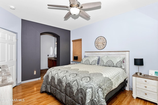 bedroom featuring ceiling fan, wood finished floors, arched walkways, and baseboards