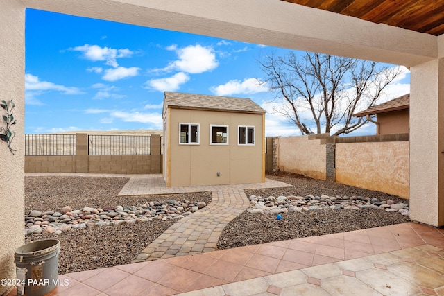 view of patio / terrace with an outdoor structure, a fenced backyard, and a shed