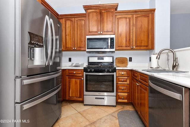 kitchen with brown cabinetry, appliances with stainless steel finishes, light countertops, and a sink