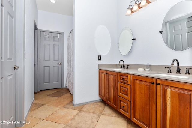 full bath featuring double vanity, baseboards, and a sink