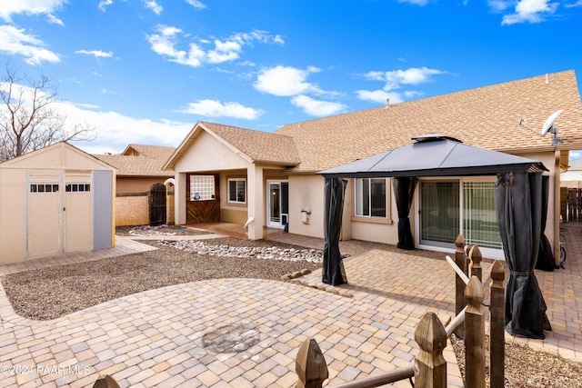 view of front of house with fence, a shed, a gazebo, an outbuilding, and a patio