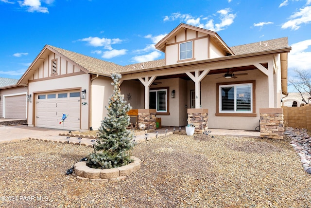 view of front of property with a shingled roof, ceiling fan, stucco siding, stone siding, and an attached garage