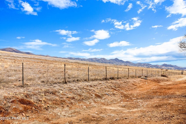 view of yard with a rural view, fence, and a mountain view