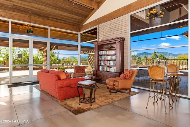 sitting room with a wealth of natural light, finished concrete floors, a mountain view, and high vaulted ceiling