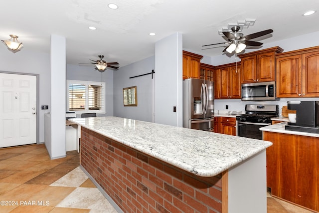 kitchen featuring brown cabinets, a ceiling fan, a kitchen island, recessed lighting, and appliances with stainless steel finishes