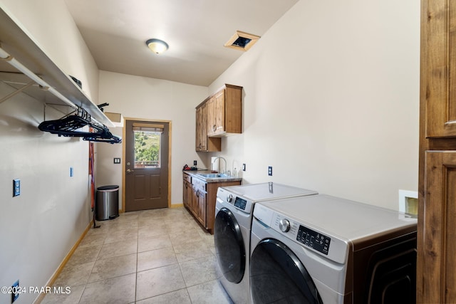 clothes washing area featuring washer and clothes dryer, light tile patterned floors, cabinets, and sink