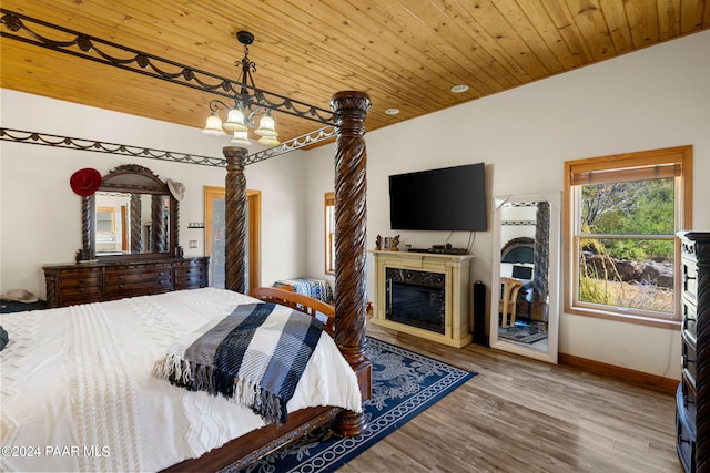 bedroom featuring a chandelier, wood-type flooring, a premium fireplace, and wood ceiling