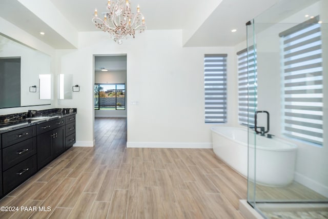 bathroom featuring hardwood / wood-style floors, vanity, a bath, and a chandelier