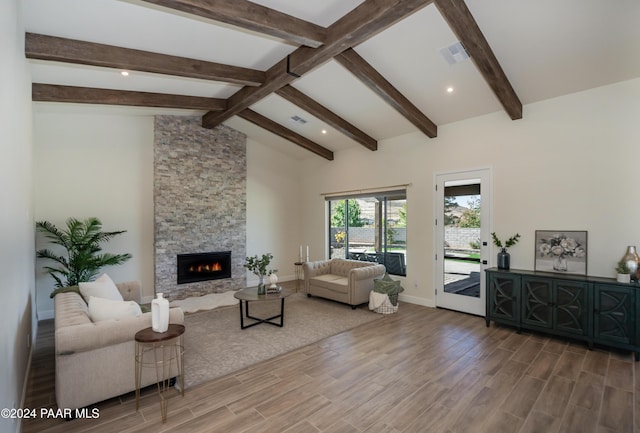 living room with a stone fireplace, lofted ceiling with beams, and hardwood / wood-style flooring