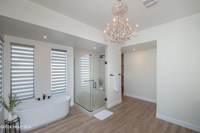 bathroom with hardwood / wood-style flooring, independent shower and bath, and a chandelier