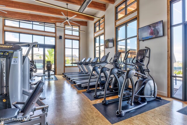 workout area with hardwood / wood-style floors, ceiling fan, and a towering ceiling