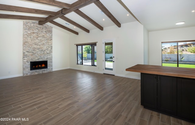 unfurnished living room with lofted ceiling with beams, dark hardwood / wood-style flooring, and a fireplace