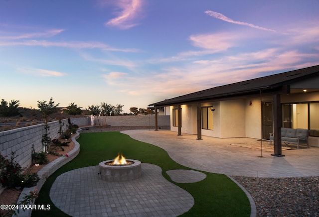 yard at dusk featuring a patio and a fire pit