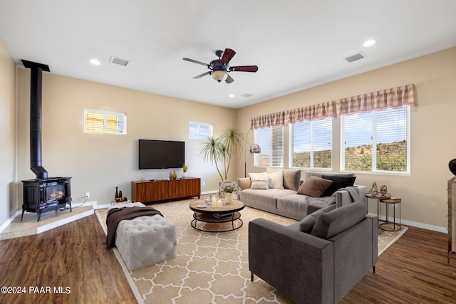 living room featuring a wood stove, ceiling fan, and hardwood / wood-style floors