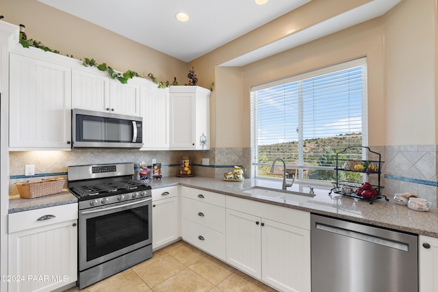 kitchen with decorative backsplash, light stone countertops, stainless steel appliances, sink, and white cabinets