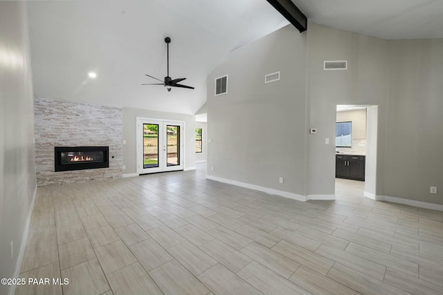 unfurnished living room featuring ceiling fan, beam ceiling, a stone fireplace, and high vaulted ceiling