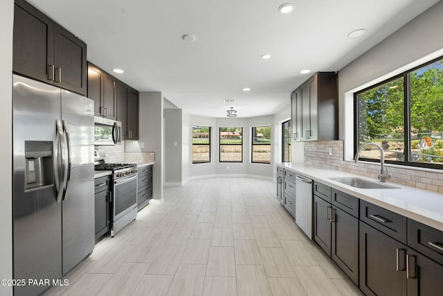 kitchen with appliances with stainless steel finishes, backsplash, dark brown cabinetry, and sink