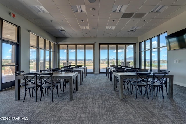 carpeted dining space with a paneled ceiling